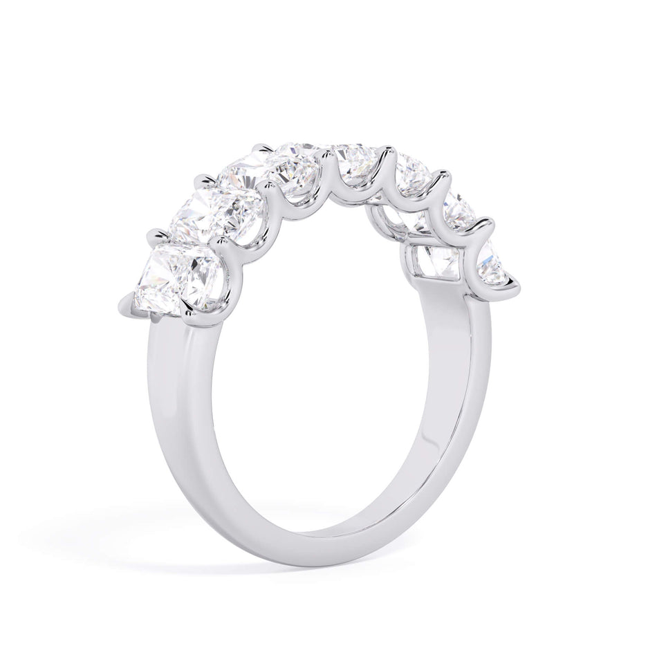 A picture of a seven stone diamond wedding ring with radiant cut diamonds that are U prong set in white gold or platinum on a white background with a slightly angled, through the finger view.