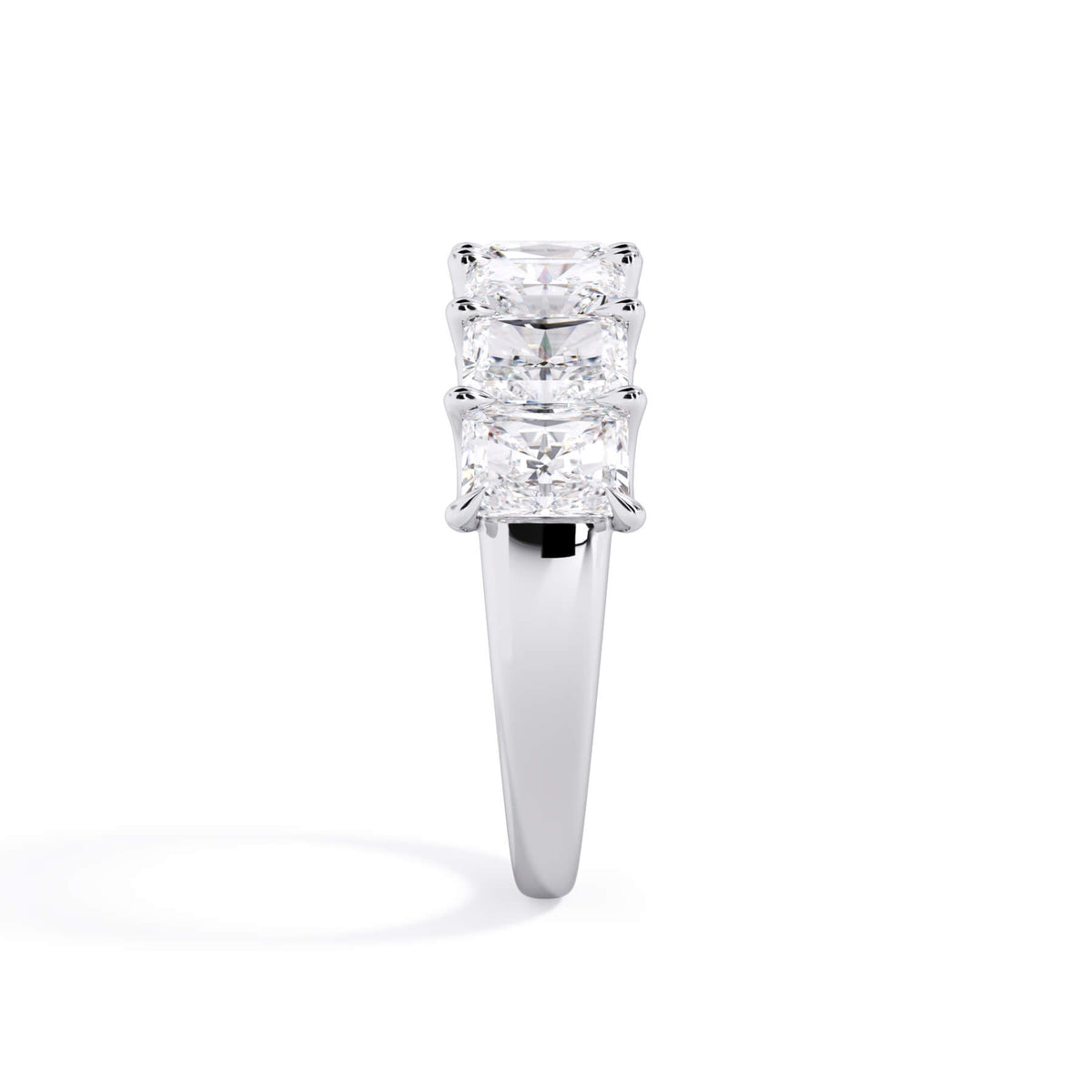 A picture of a seven stone diamond wedding ring with radiant cut diamonds that are U prong set in white gold or platinum on a white background with a side profile view.