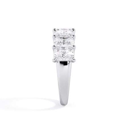 A picture of a seven stone diamond wedding ring with radiant cut diamonds that are U prong set in white gold or platinum on a white background with a side profile view.
