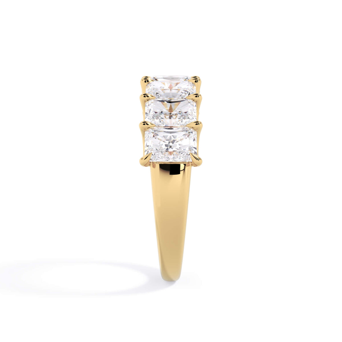A picture of a seven stone diamond wedding ring with radiant cut diamonds that are U prong set in yellow gold on a white background with a side profile view.