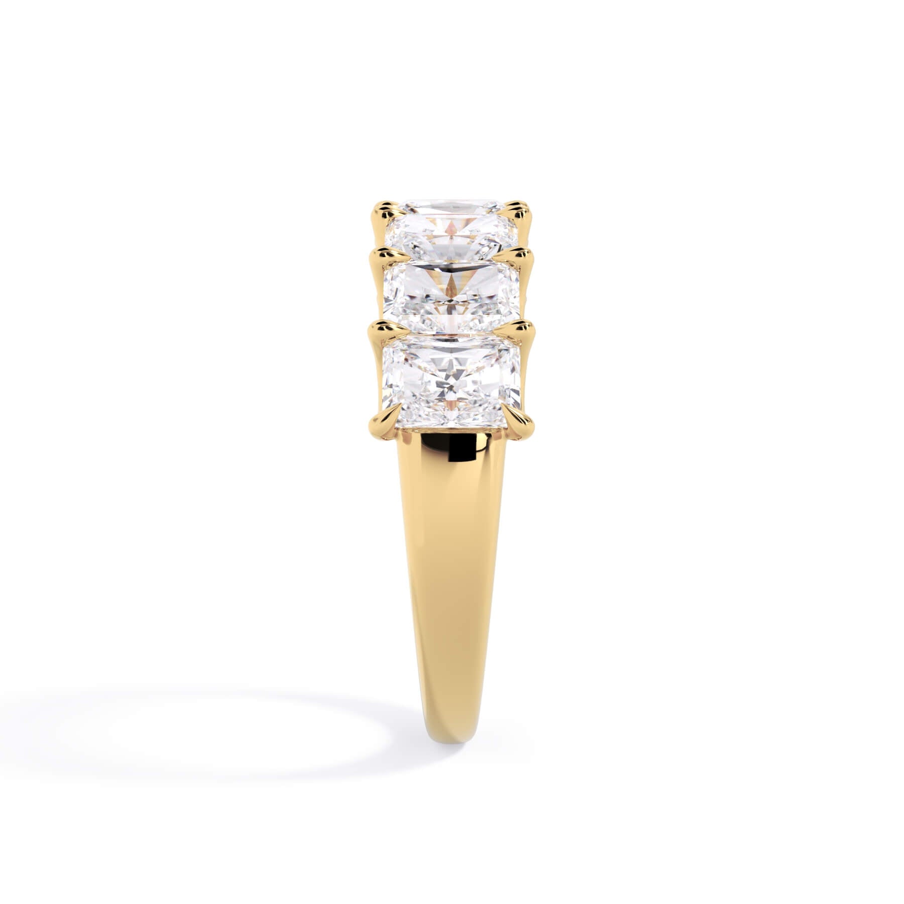 A picture of a seven stone diamond wedding ring with radiant cut diamonds that are U prong set in yellow gold on a white background with a side profile view.