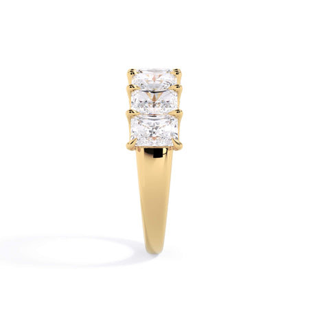 A picture of a seven stone diamond wedding ring with radiant cut diamonds that are U prong set in yellow gold on a white background with a side profile view.