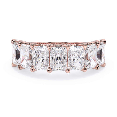 A picture of a seven stone diamond wedding ring with radiant cut diamonds that are U prong set in rose gold on a white background with the ring facing forward, lying down.