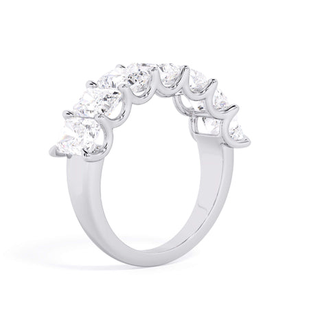A picture of a seven stone diamond wedding ring with radiant cut diamonds that are U prong set in white gold or platinum on a white background with the ring facing forward, lying down.