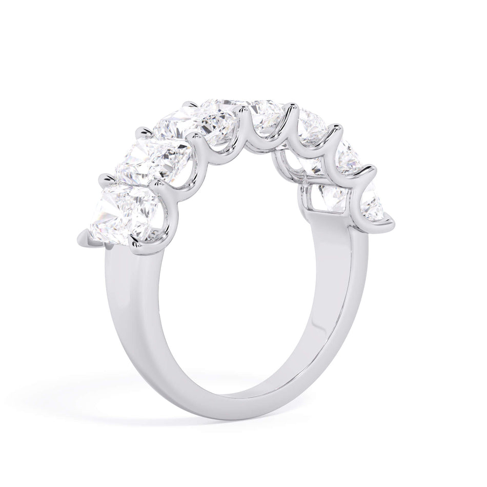 A picture of a seven stone diamond wedding ring with radiant cut diamonds that are U prong set in white gold or platinum on a white background with the ring facing forward, lying down.