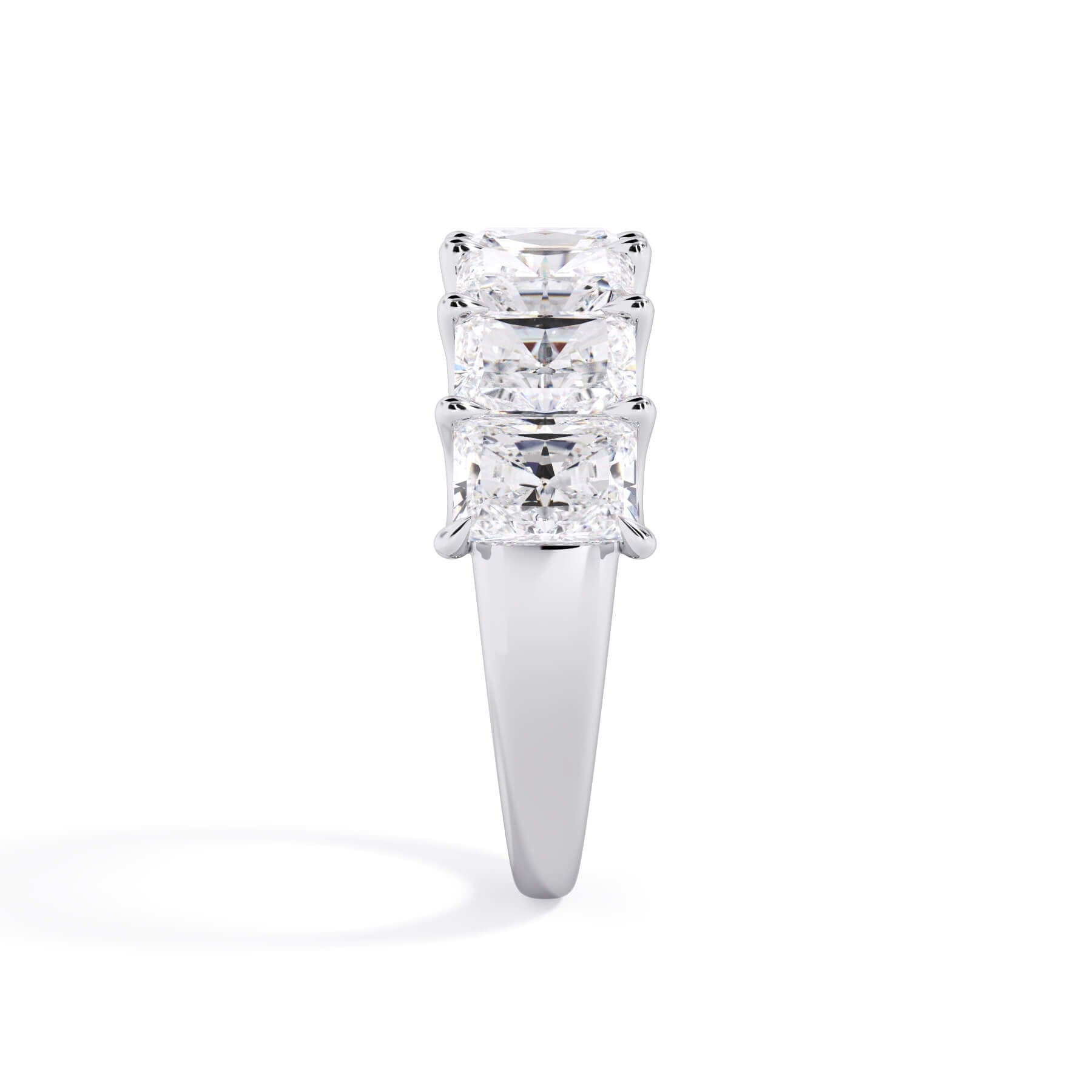 A picture of a seven stone diamond wedding ring with radiant cut diamonds that are U prong set in white gold or platinum on a white background with the ring facing forward, lying down.
