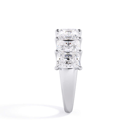A picture of a seven stone diamond wedding ring with radiant cut diamonds that are U prong set in white gold or platinum on a white background with the ring facing forward, lying down.