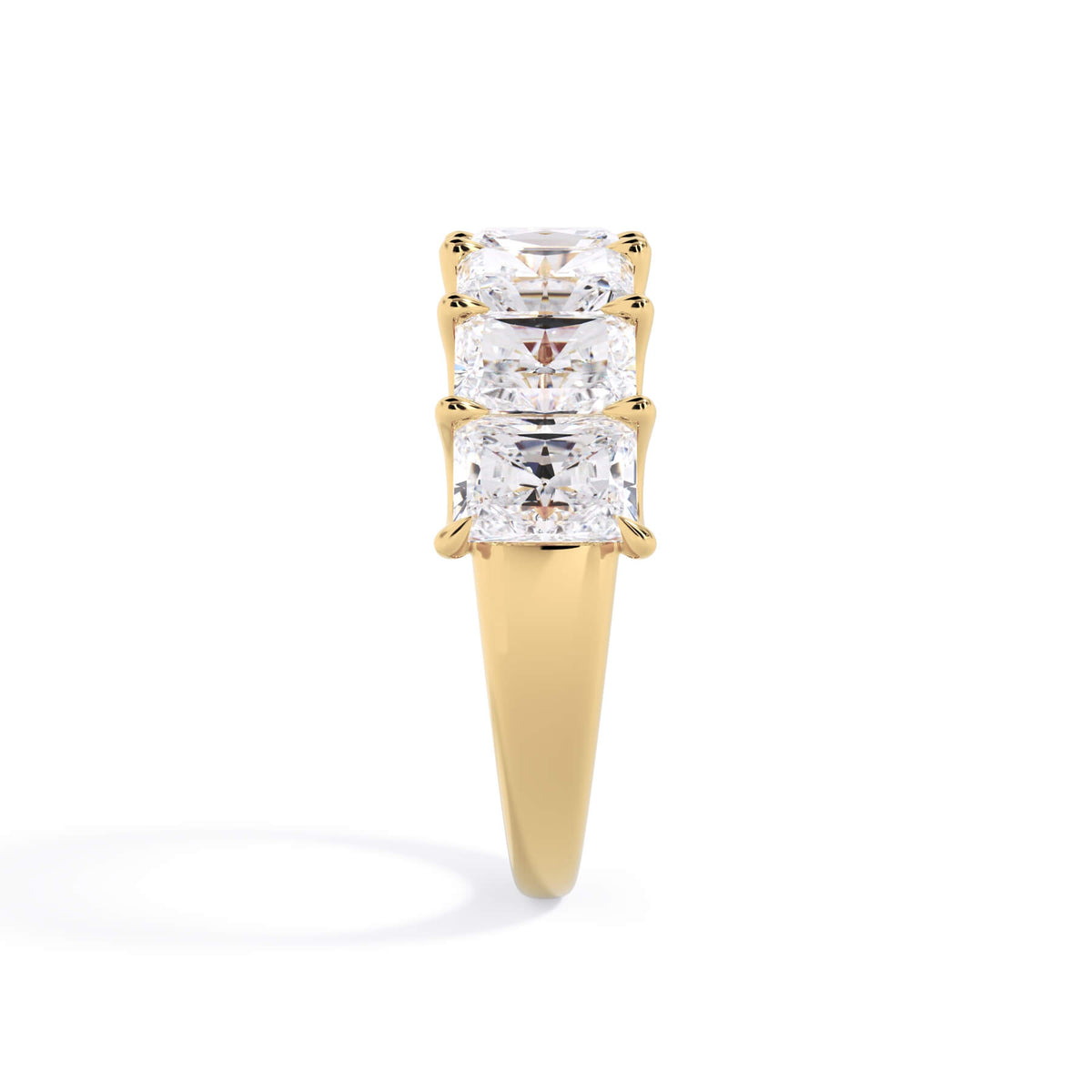 A picture of a seven stone diamond wedding ring with radiant cut diamonds that are U prong set in yellow gold on a white background with a side profile view.