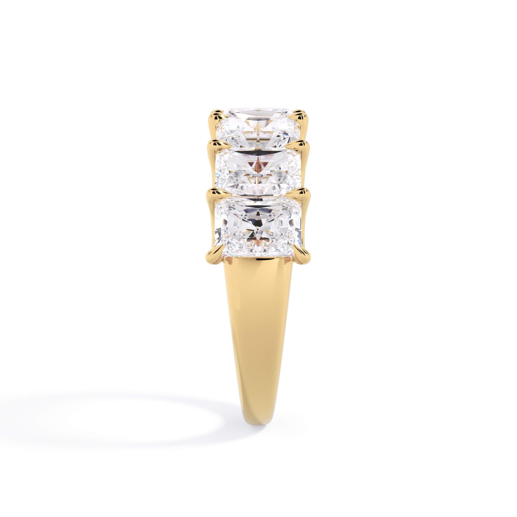 A picture of a seven stone diamond wedding ring with radiant cut diamonds that are U prong set in yellow gold on a white background with a side profile view.