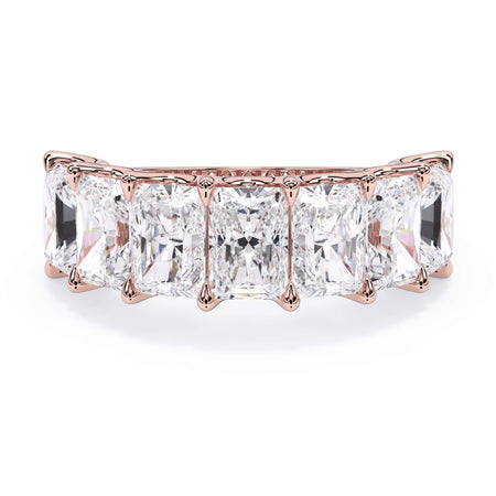 A picture of a seven stone diamond wedding ring with radiant cut diamonds that are U prong set in rose gold on a white background with the ring facing forward, lying down.
