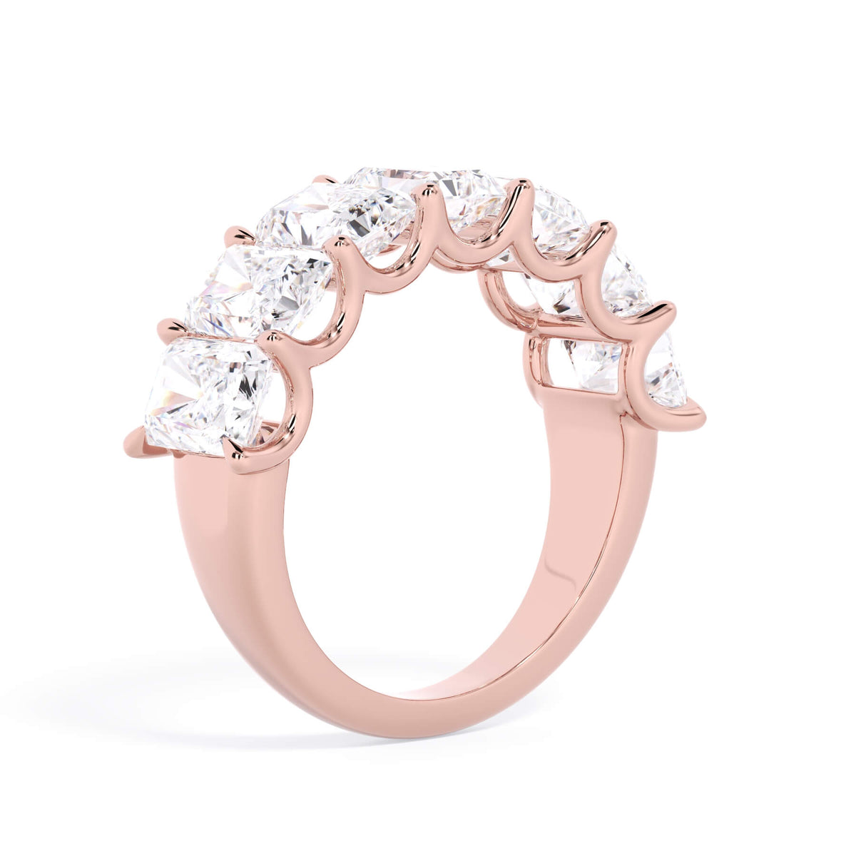 A picture of a seven stone diamond wedding ring with radiant cut diamonds that are U prong set in rose gold on a white background with a slightly angled, through the finger view.