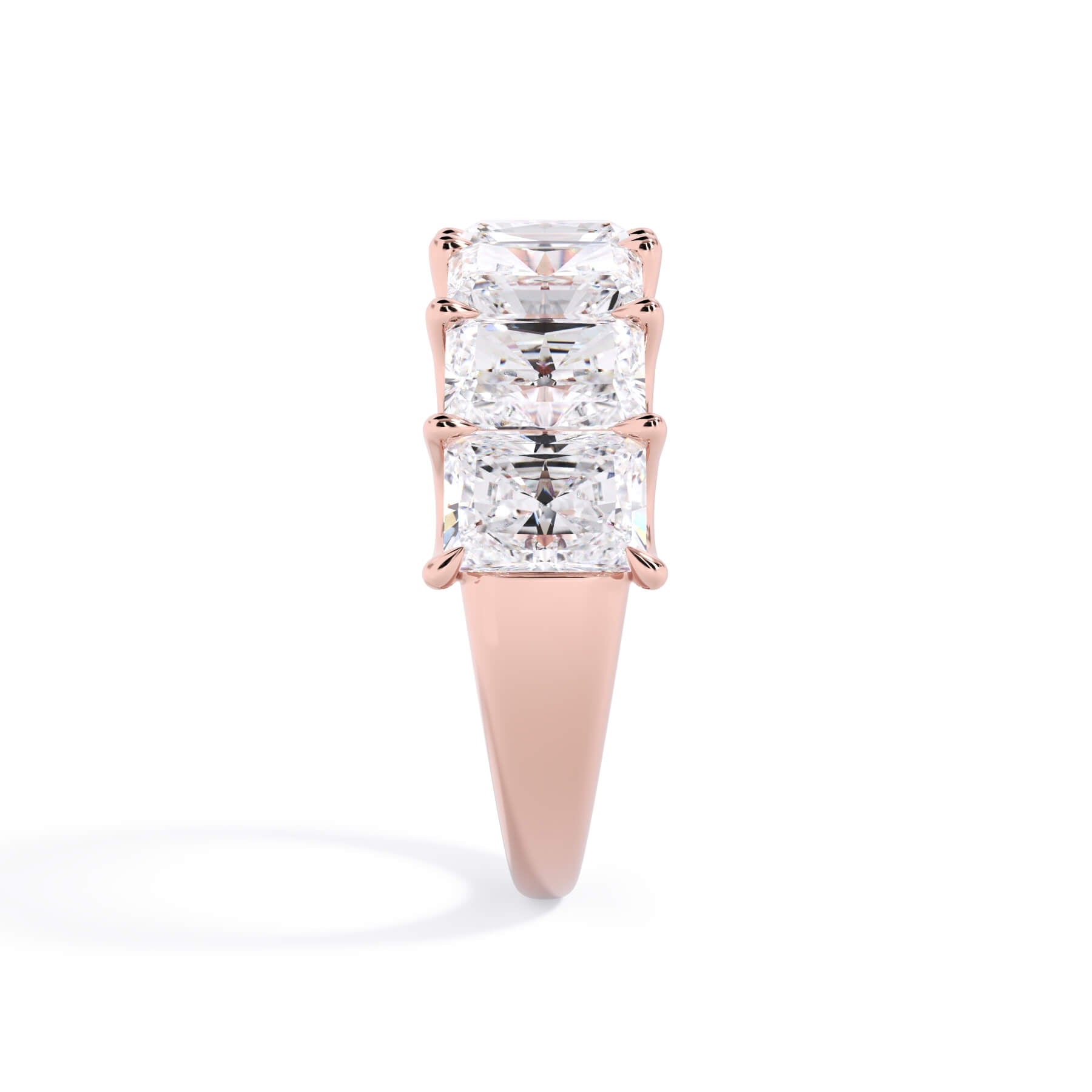 A picture of a seven stone diamond wedding ring with radiant cut diamonds that are U prong set in rose gold on a white background with a side profile view.