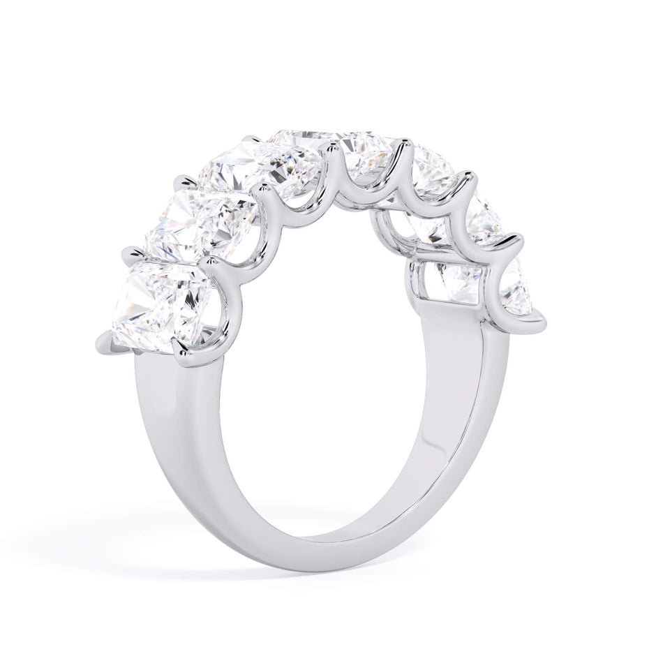 A picture of a seven stone diamond wedding ring with radiant cut diamonds that are U prong set in white gold or platinum on a white background with a slightly angled, through the finger view.