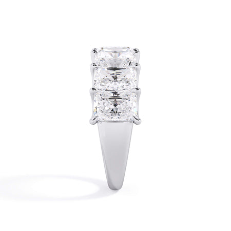 A picture of a seven stone diamond wedding ring with radiant cut diamonds that are U prong set in white gold or platinum on a white background with a side profile view.
