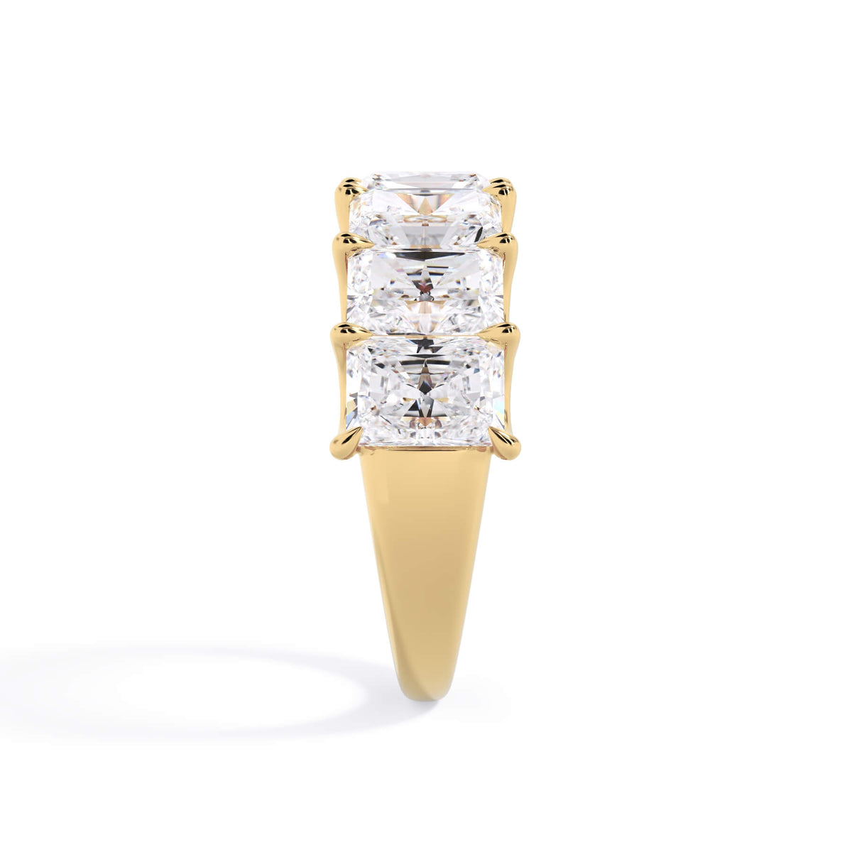 A picture of a seven stone diamond wedding ring with radiant cut diamonds that are U prong set in yellow gold on a white background with a side profile view.