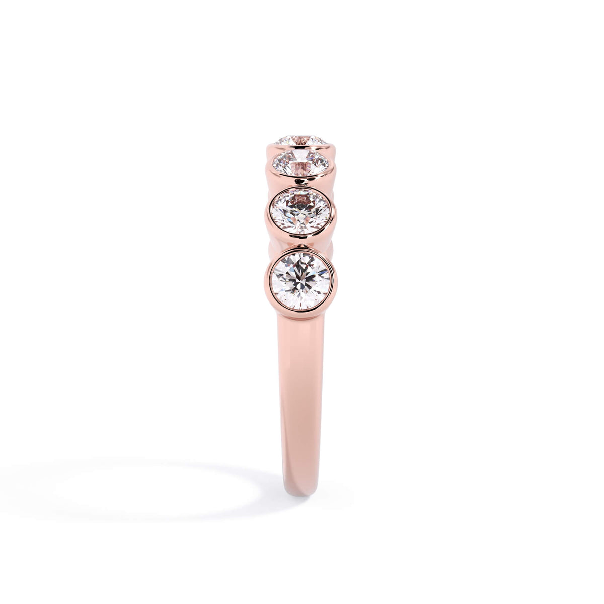 A picture of a seven stone diamond wedding ring with round diamonds that are bezel set in rose gold on a white background with a side profile view.