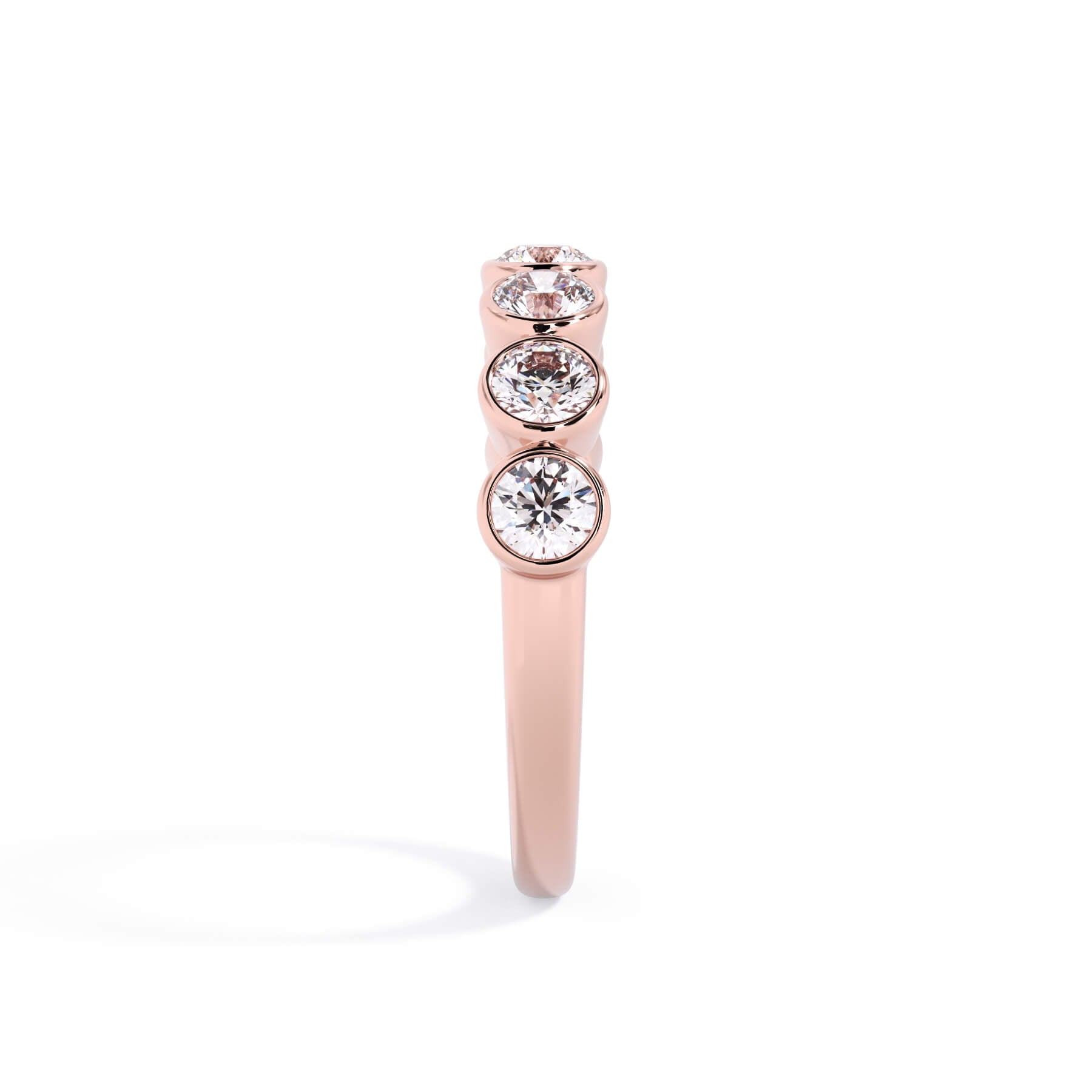 A picture of a seven stone diamond wedding ring with round diamonds that are bezel set in rose gold on a white background with a side profile view.