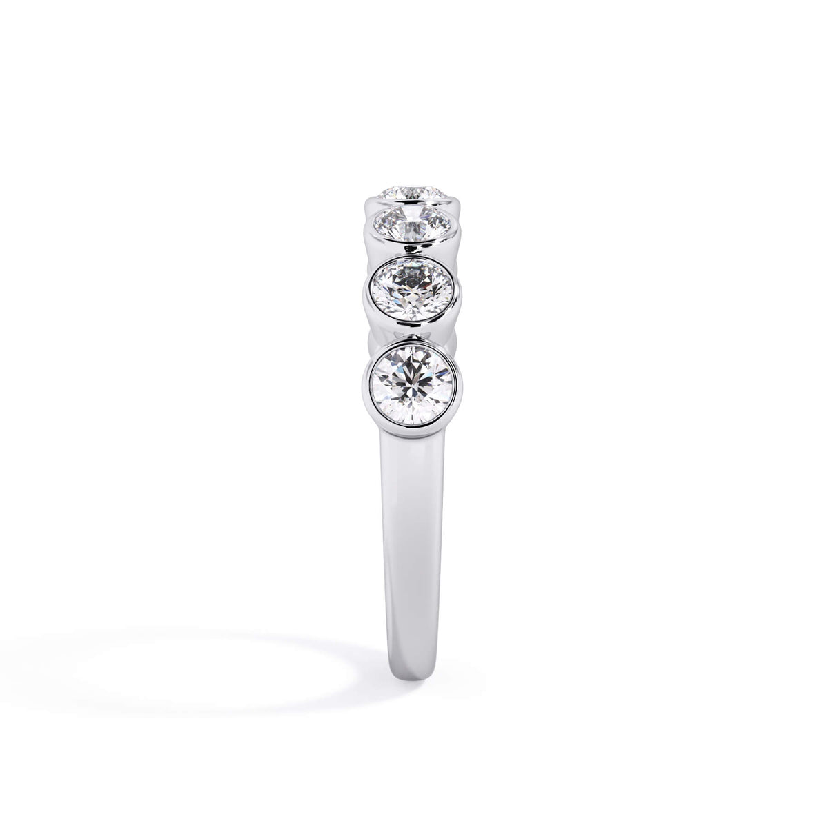 A picture of a seven stone diamond wedding ring with round diamonds that are bezel set in white gold or platinum on a white background with a side profile view.
