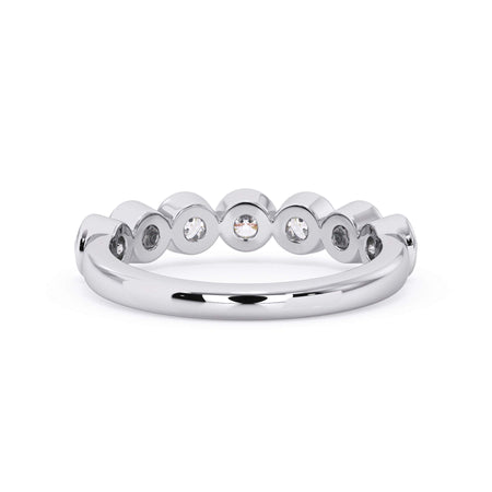 A picture of a seven stone diamond wedding ring with round diamonds that are bezel set in white gold or platinum on a white background with a view of the underside of the ring.