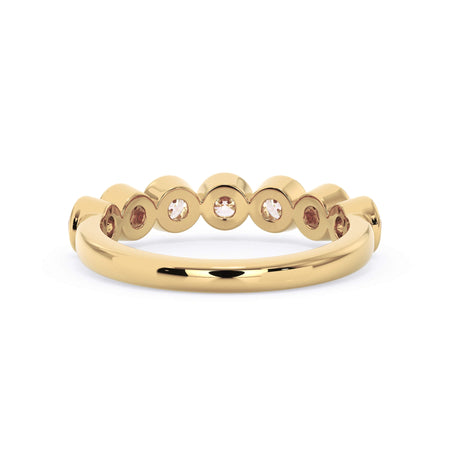 A picture of a seven stone diamond wedding ring with round diamonds that are bezel set in yellow gold on a white background with a view of the underside of the ring.
