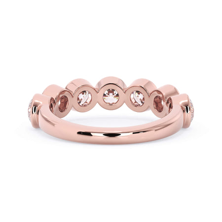 A picture of a seven stone diamond wedding ring with round diamonds that are bezel set in rose gold on a white background with a view of the underside of the ring.