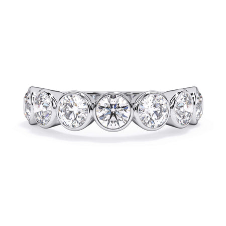 A picture of a seven stone diamond wedding ring with round diamonds that are bezel set in white gold or platinum on a white background with the ring facing forward, lying down.