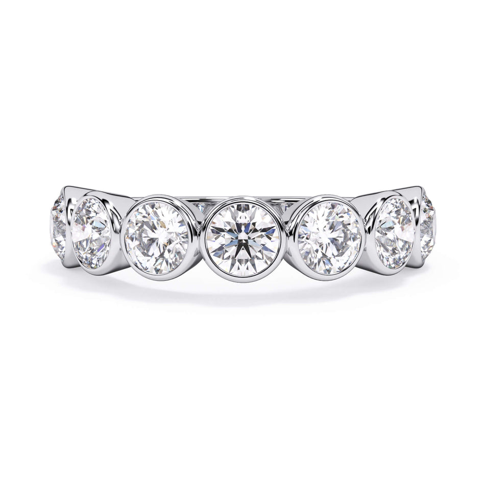 A picture of a seven stone diamond wedding ring with round diamonds that are bezel set in white gold or platinum on a white background with the ring facing forward, lying down.