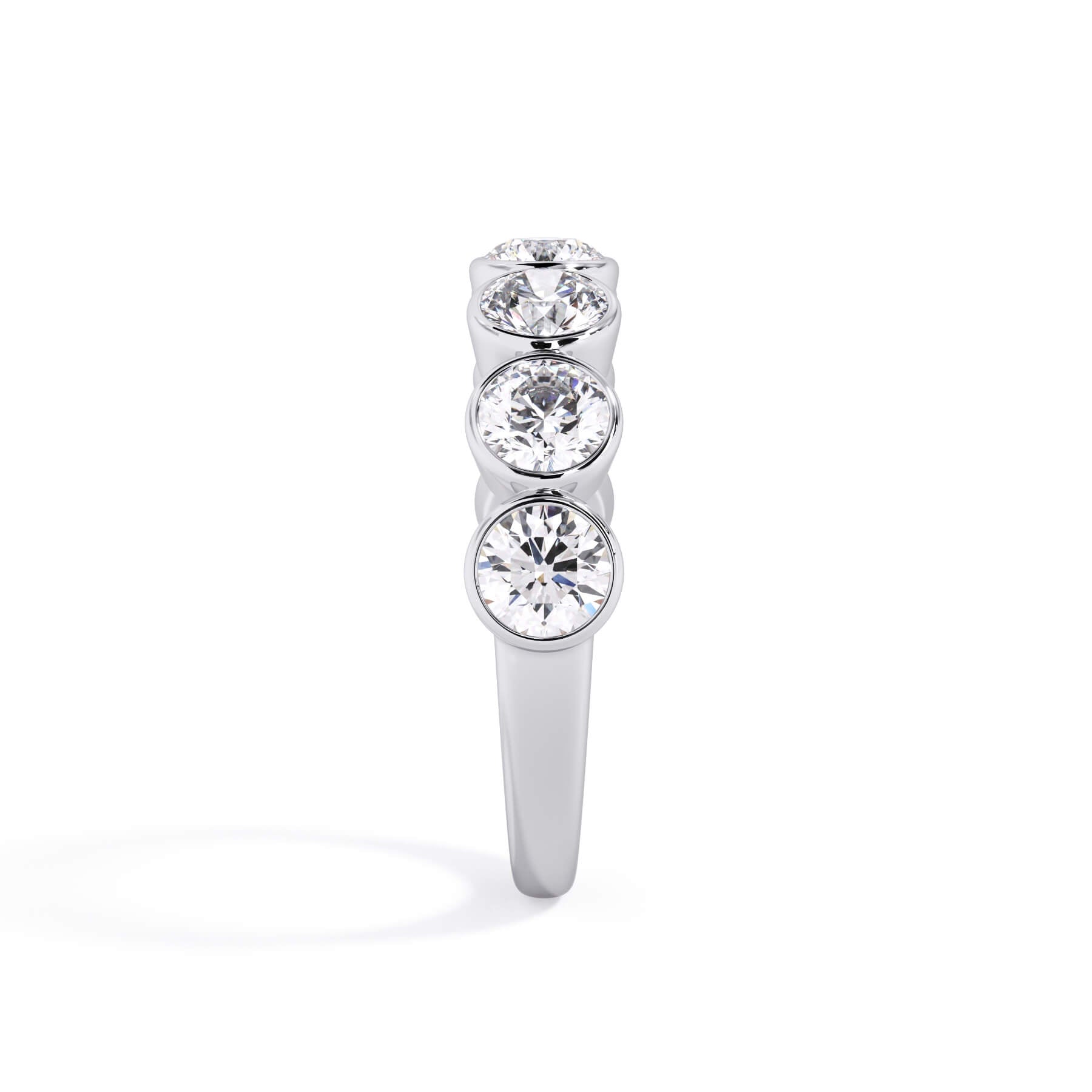 A picture of a seven stone diamond wedding ring with round diamonds that are bezel set in white gold or platinum on a white background with a side profile view.