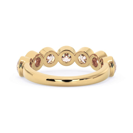 A picture of a seven stone diamond wedding ring with round diamonds that are bezel set in yellow gold on a white background with a view of the underside of the ring.