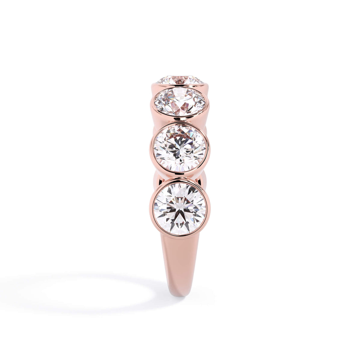 A picture of a seven stone diamond wedding ring with round diamonds that are bezel set in rose gold on a white background with a side profile view.