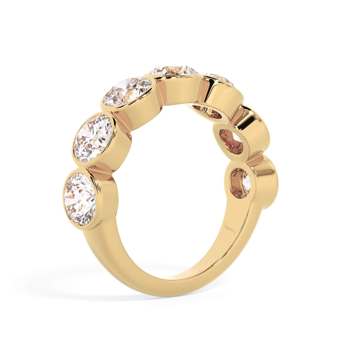 A picture of a seven stone diamond wedding ring with round diamonds that are bezel set in yellow gold on a white background with a slightly angled, through the finger view.