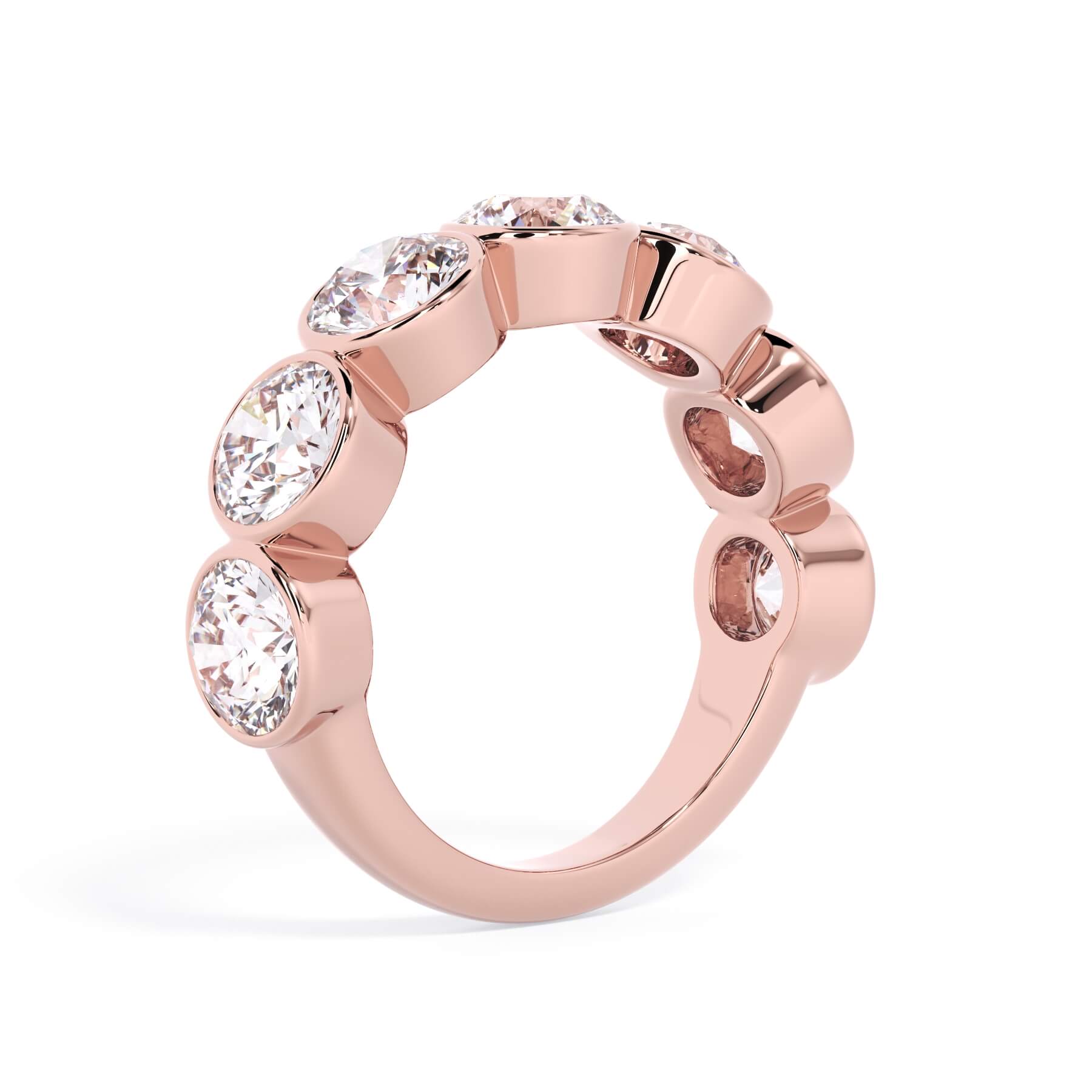 A picture of a seven stone diamond wedding ring with round diamonds that are bezel set in rose gold on a white background with a slightly angled, through the finger view.