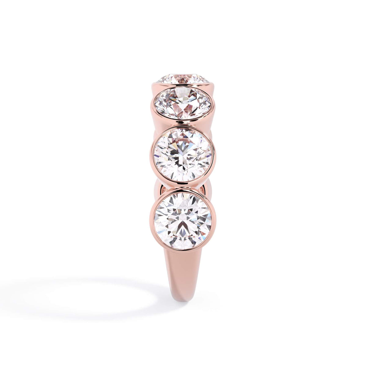 A picture of a seven stone diamond wedding ring with round diamonds that are bezel set in rose gold on a white background with a side profile view.