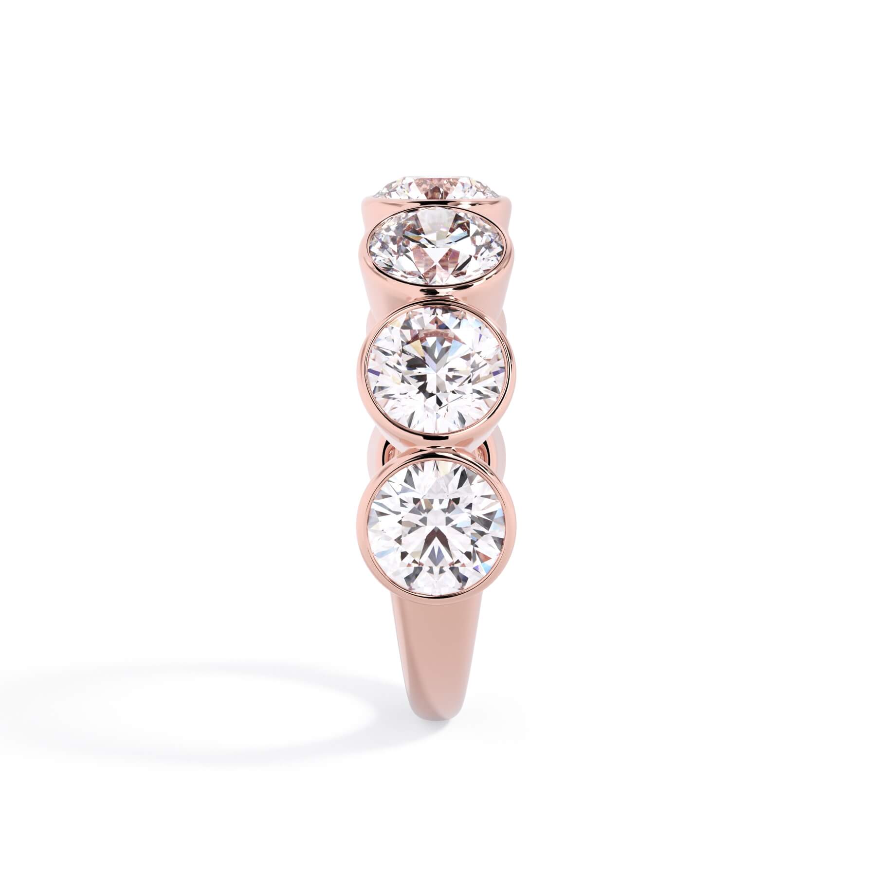 A picture of a seven stone diamond wedding ring with round diamonds that are bezel set in rose gold on a white background with a side profile view.