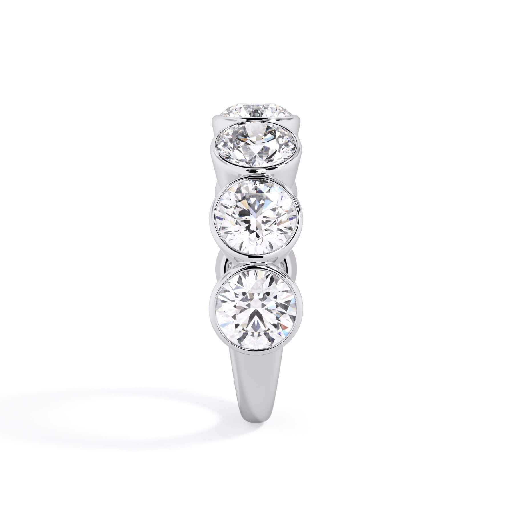 A picture of a seven stone diamond wedding ring with round diamonds that are bezel set in white gold or platinum on a white background with a side profile view.