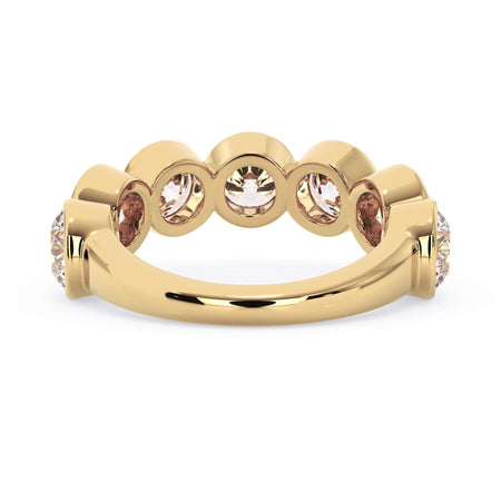 A picture of a seven stone diamond wedding ring with round diamonds that are bezel set in yellow gold on a white background with a view of the underside of the ring.