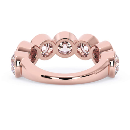 A picture of a seven stone diamond wedding ring with round diamonds that are bezel set in rose gold on a white background with a view of the underside of the ring.