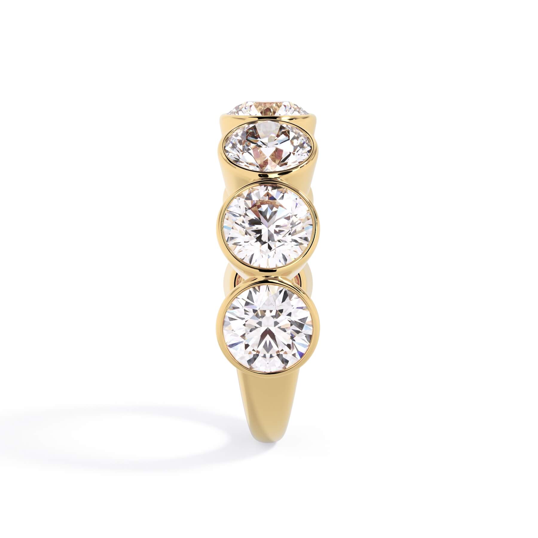 A picture of a seven stone diamond wedding ring with round diamonds that are bezel set in yellow gold on a white background with a side profile view.