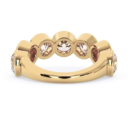 A picture of a seven stone diamond wedding ring with round diamonds that are bezel set in yellow gold on a white background with a view of the underside of the ring.