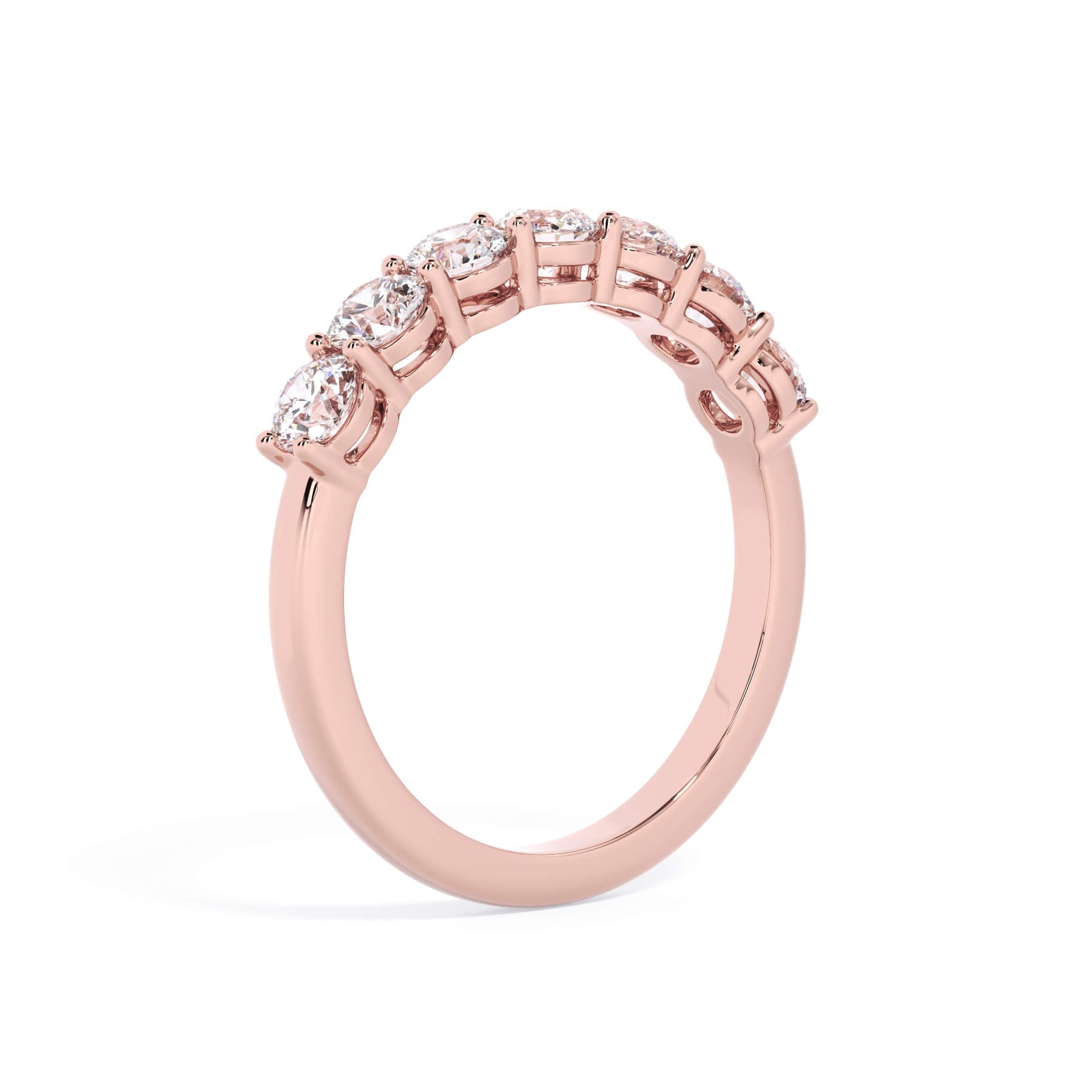 A picture of a seven stone diamond wedding ring with round diamonds that are shared prong set in rose gold on a white background with a slightly angled, through the finger view.
