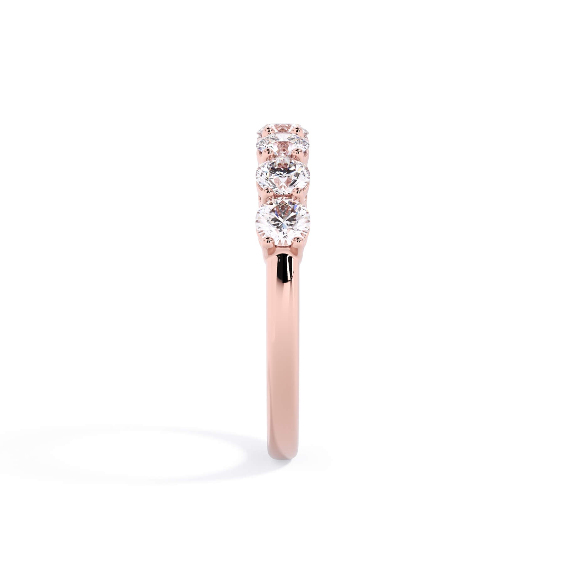 A picture of a seven stone diamond wedding ring with round diamonds that are shared prong set in rose gold on a white background with a side profile view.