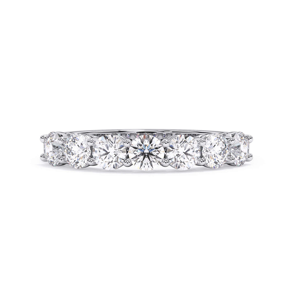 A picture of a seven stone diamond wedding ring with round diamonds that are shared prong set in white gold or platinum on a white background with the ring facing forward, lying down.