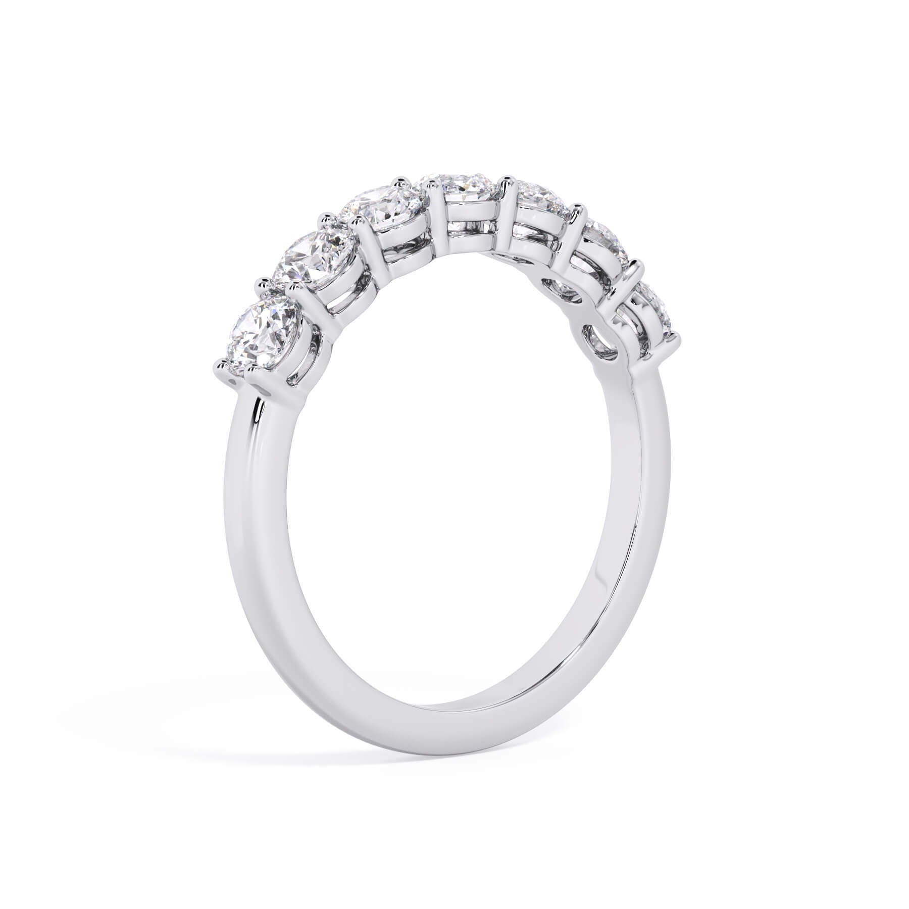 A picture of a seven stone diamond wedding ring with round diamonds that are shared prong set in white gold or platinum on a white background with a slightly angled, through the finger view.