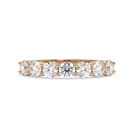 A picture of a seven stone diamond wedding ring with round diamonds that are shared prong set in yellow gold on a white background with the ring facing forward, lying down.
