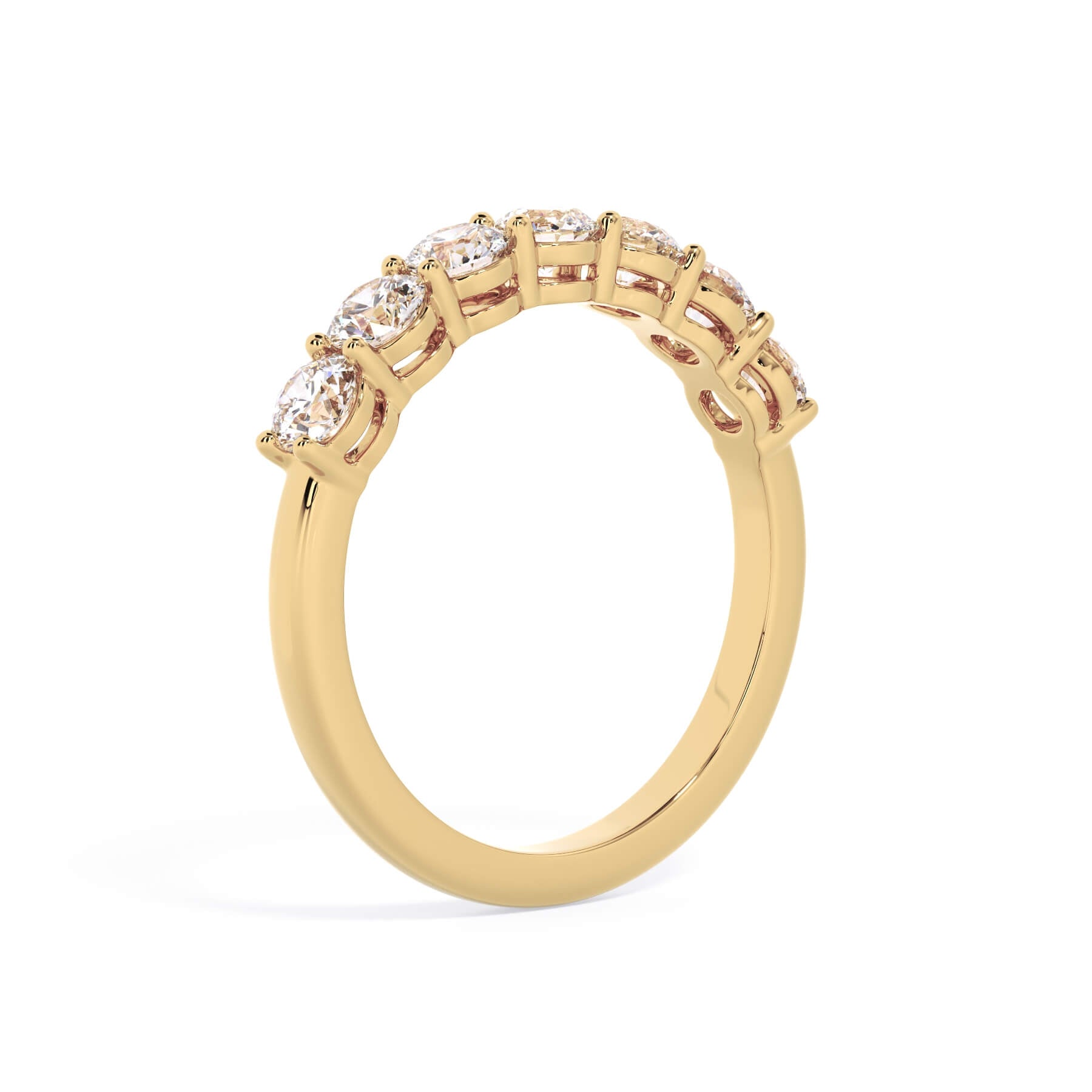 A picture of a seven stone diamond wedding ring with round diamonds that are shared prong set in yellow gold on a white background with a slightly angled, through the finger view.