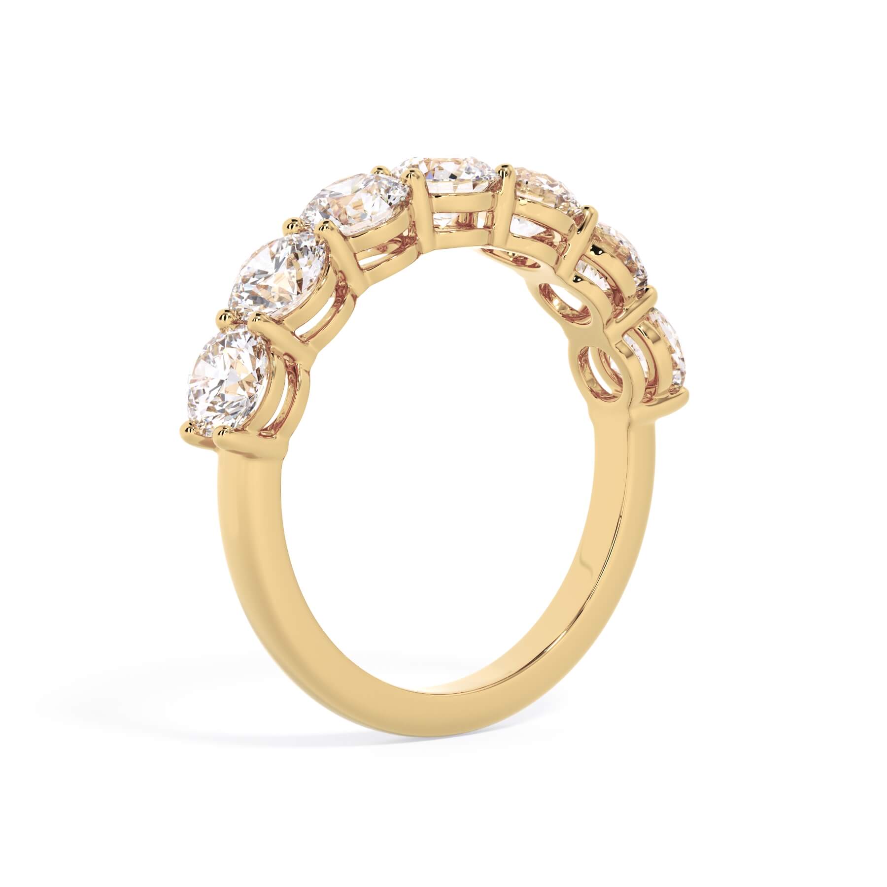 A picture of a seven stone diamond wedding ring with round diamonds that are shared prong set in yellow gold on a white background with a slightly angled, through the finger view.