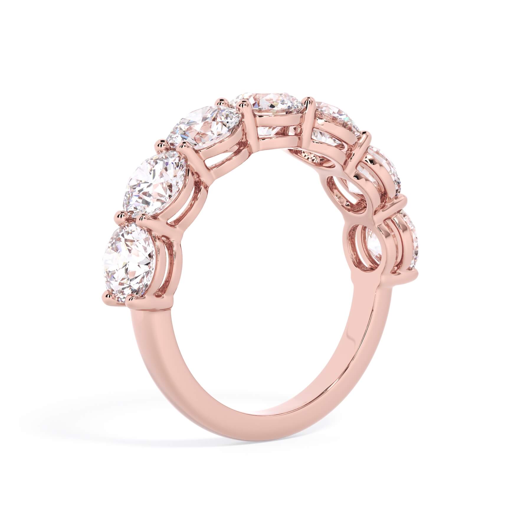 A picture of a seven stone diamond wedding ring with round diamonds that are shared prong set in rose gold on a white background with a slightly angled, through the finger view.