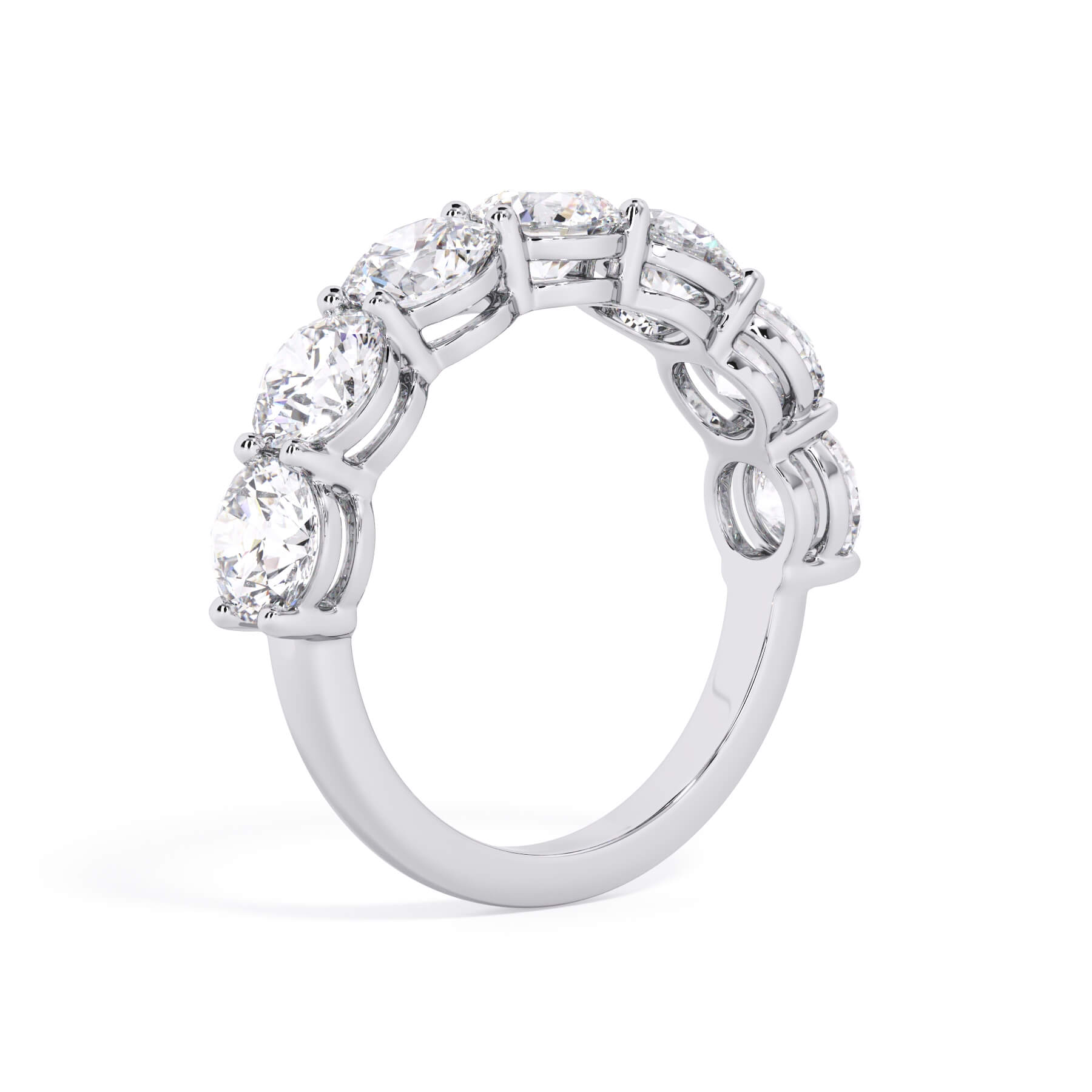A picture of a seven stone diamond wedding ring with round diamonds that are shared prong set in white gold or platinum on a white background with a slightly angled, through the finger view.