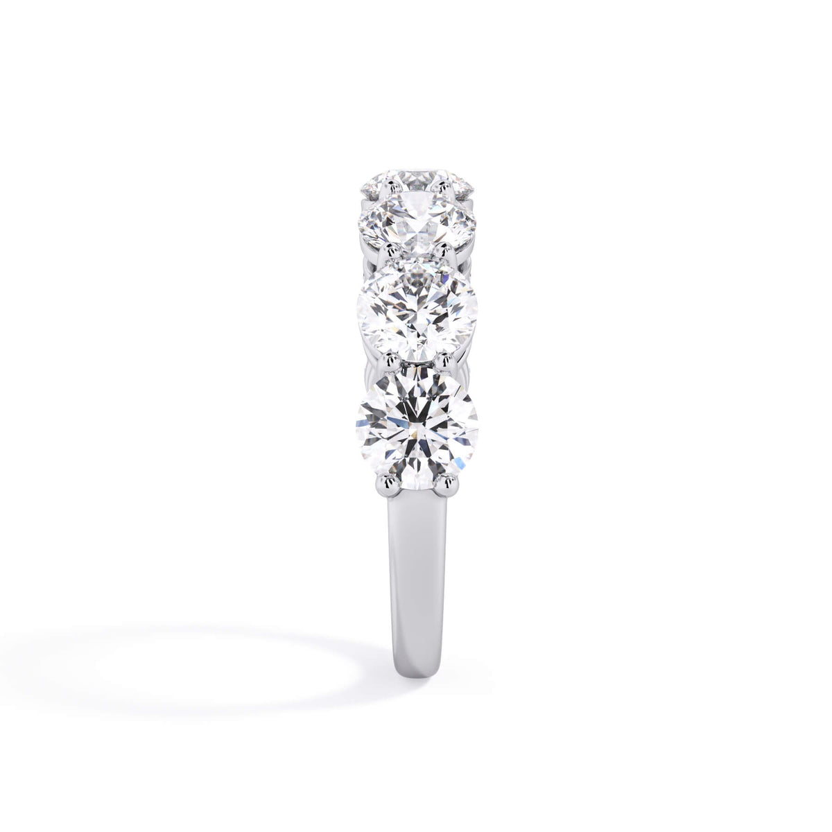 A picture of a seven stone diamond wedding ring with round diamonds that are shared prong set in white gold or platinum on a white background with a side profile view.