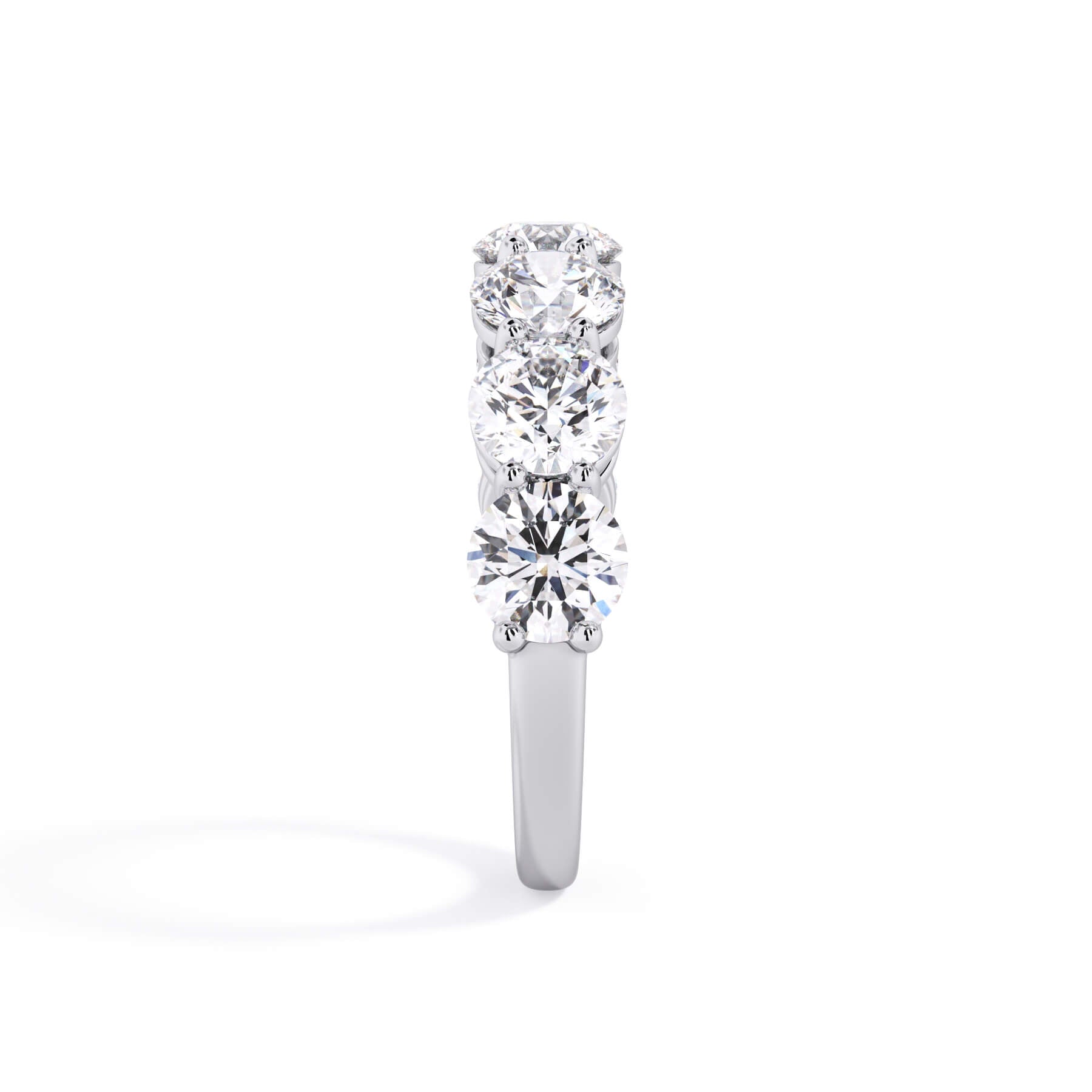 A picture of a seven stone diamond wedding ring with round diamonds that are shared prong set in white gold or platinum on a white background with a side profile view.